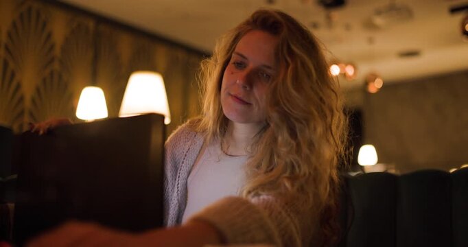 NS girl focused on lap top in a cozy cafe setting, enjoying a moment of relaxation while working and smoking a cigarette during the evening