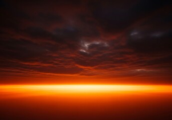 Fototapeta premium A dramatic sunset featuring deep red clouds hovering above a glowing golden horizon at twilight