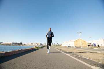 Obraz premium Black man running on urban path near the water