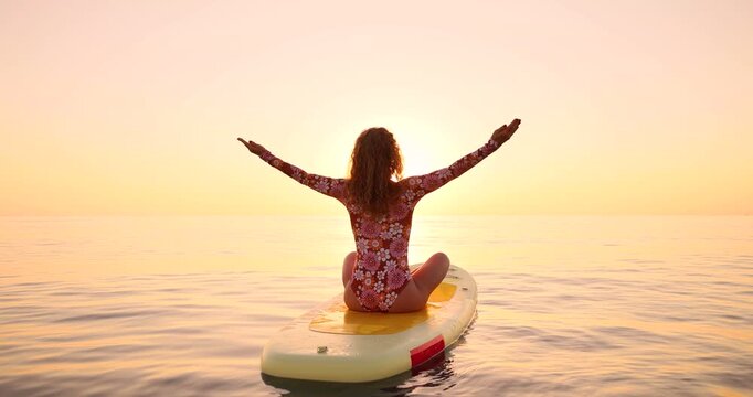 A happy young woman walking on a sup board by the sea during her summer vacation. Slow motion
