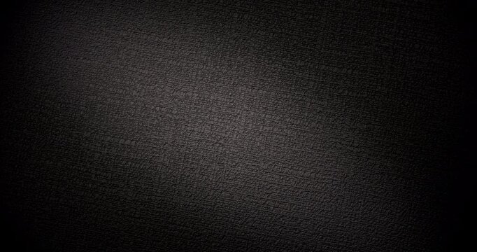 Black Texture Abstract. Slow smooth rotation of dark textured surface with fine grain pattern gently moving under dramatic directional light creating subtle highlights and deep shadows.