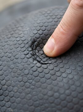Close-up of a finger pressing a textured surface with a concave indentation
