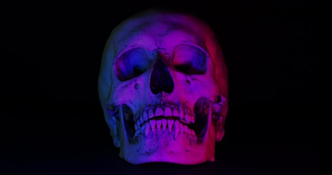 Human Skull with Color Lights . Video of motionless human skull with dramatic color-changing color lights on black background.