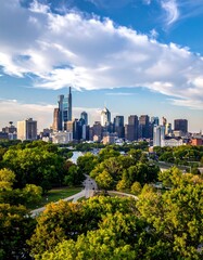 Obraz premium Metropolitan cityscape framed by lush trees under a vibrant sky with scattered clouds