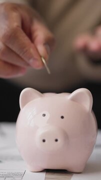 Control finance and save money, close up view of funny piggy bank and male hand putting coins. Salary and incomes for working people, unemployment benefits for unemployed, ceramic money-box on table