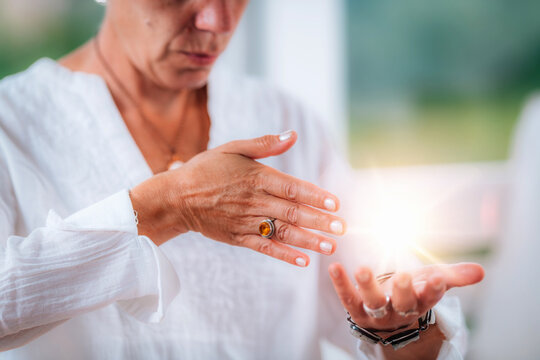 Mindfulness meditation energy healing practice where a woman channels symbolic healing light between her hands. The gesture represents holistic therapy, spiritual balance, and inner wellness.