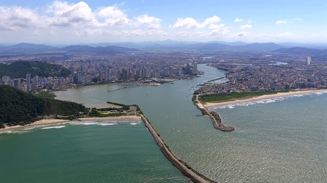 Itajai and Navegantes at the Itajai Acu River mouth with harbor breakwaters, dense urban coastline and Atlantic shoreline in Santa Catarina, Brazil, port city landscape, aerial view, slow pan, high an