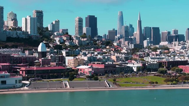 Aerial daytime view of San Francisco&rsquo;s waterfront skyline near Aquatic Park and Ghirardelli Square, featuring Salesforce Tower, the Transamerica Pyramid, hillside homes, and bayfront scenery.
