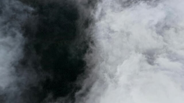 Top down shot above the clouds, sky opening while clouds disperse revealing Latvian land
