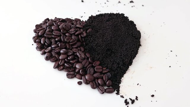 Heart shape made of roasted coffee beans and dark ground coffee on a white background