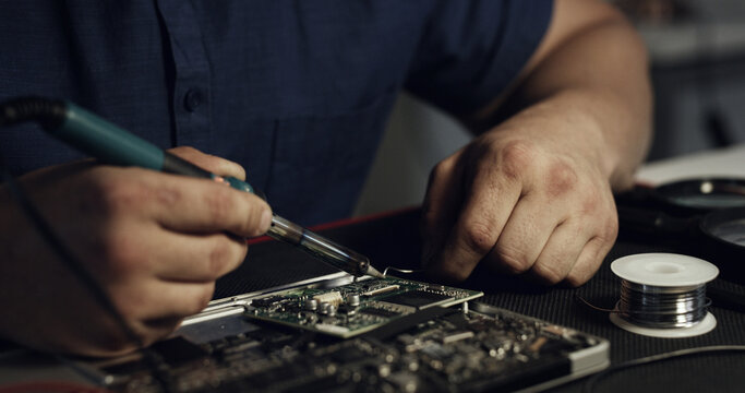 Soldering, repair or hands in workshop with circuit board, inspection or wiring assemble in hardware check. Electronics, man or engineer with tech, motherboard testing or maintenance in system fix.