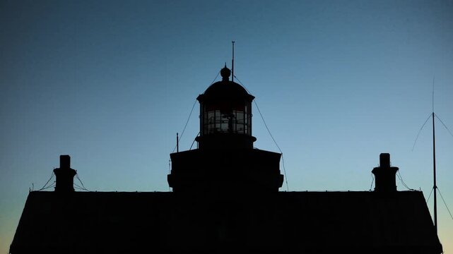 Close view silhouette of Stora Karls&ouml; lighthouse with flashing beacon light in darkness against blue evening sky, Gotland Sweden