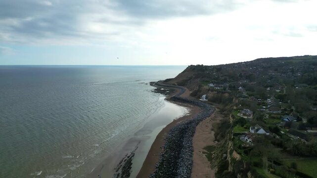 Slow motion drone shot gliding through seagulls over Fairlight Cove beach, East Sussex, UK in sunny spring conditions.