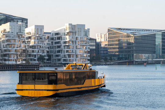 Harbor waterfront scene with boat and modern apartments shaping urban Copenhagen Denmark linking Havnestad with Havneholmen in a renewed district