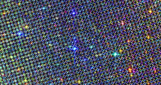 Seamless Rotating Rainbow Rhinestone Grid. Macro video of faceted crystals with vibrant rainbow shimmer and smooth rotational camera movement on dark surface.