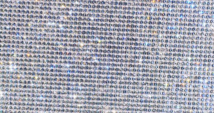 Rotating Sparkling Rhinestone. Macro video of faceted crystals sparkling intensely with smooth rotational camera movement on white surface.