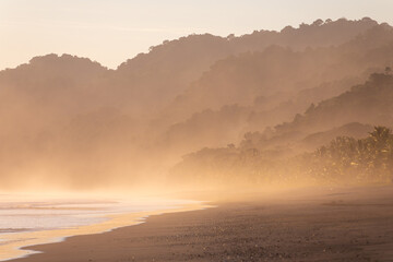 The low sun's golden light illuminates the ocean spray on Carate Beach, with views of Corcovado NP at sunset. Costa Rica. © jiriviehmann