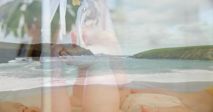 Mom placing hands on baby foot, rubbing to calm with coastal waves health overlay ring visible
