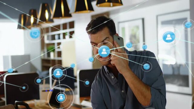 Receiving alert, man in navy shirt holding phone tapping tablet monitoring network in open office