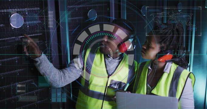 Pointing techs in hivis red muffs tapping round rack control checking laptop via HUD in datacenter