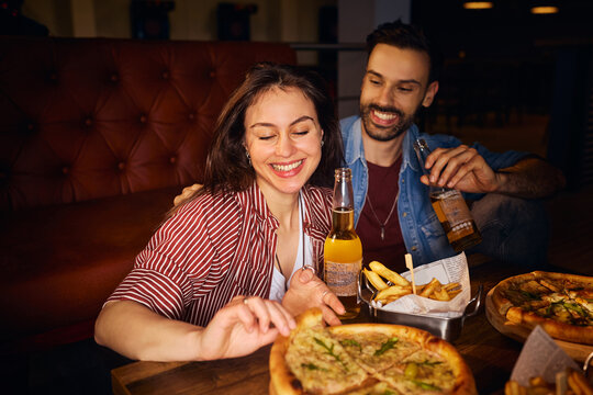 Happy woman eating pizza on date night with her boyfriend.