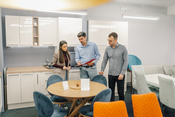 Obraz premium Salesperson consulting couple choosing kitchen furniture in showroom