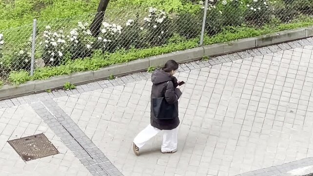 Mujer nomof&oacute;bica y adicta al tel&eacute;fono m&oacute;vil caminando absorta y distraida por acera