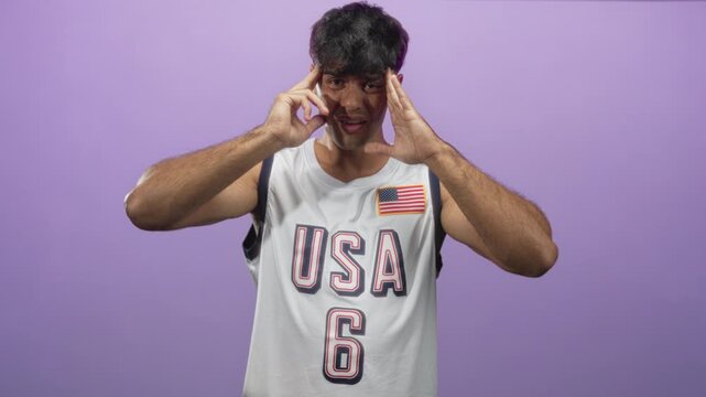 Man in usa basketball jersey holds hands to temples in studio for headache; competitive frustration pressure.