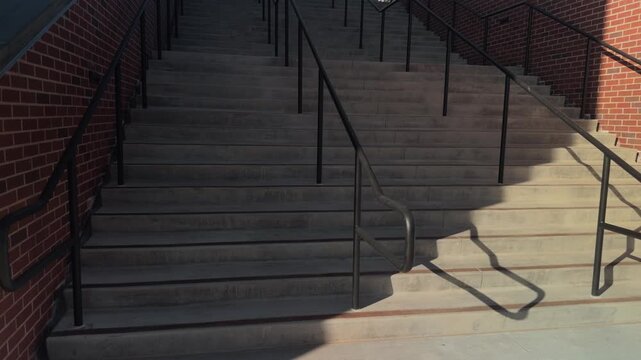 Slow motion forward glide rising up wide concrete stairs framed by brick walls and railings