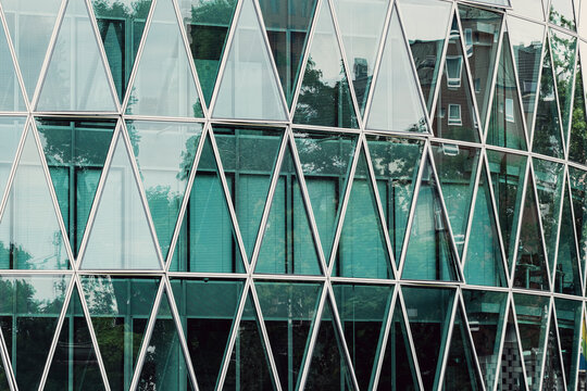 Abstract triangles geometry across modern glass facade highlights architecture structure and repeating pattern for contemporary design background detail closeup