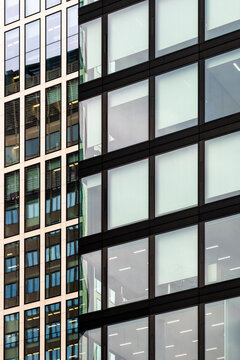 Abstract view of office interior behind grid windows on modern corporate building facade showcasing clean architecture and workplace concept detail