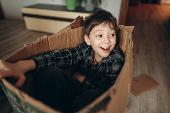 Child playing and smiling inside a cardboard box at home