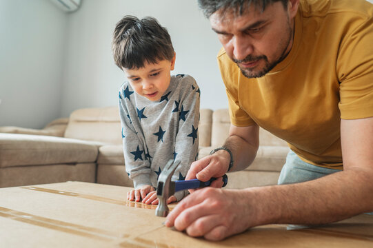 Father and child assembling furniture together at home