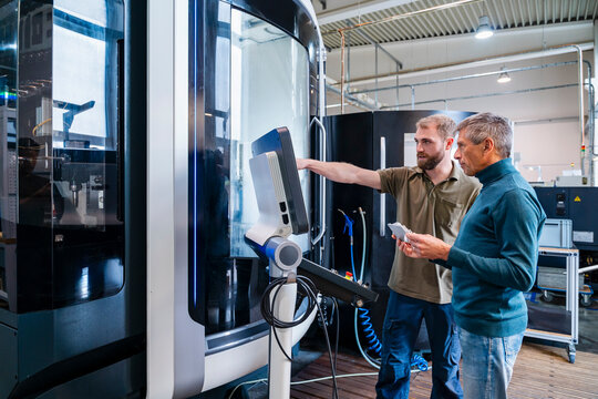 Two men discussing a machine system in a production hall