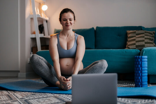 Pregnant woman practicing prenatal yoga at home with online course