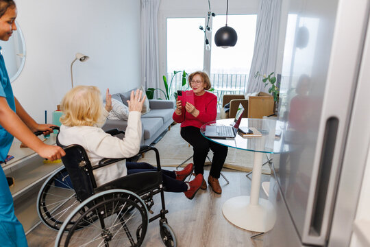 Senior in wheelchair with caregiver and therapist doing therapy at home