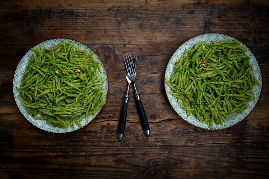 Trofie pasta with pesto alla genovese and pine nuts on dark wood table