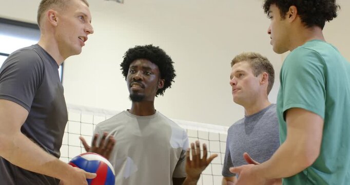 Male teammates nodding stacking hands cheering moving on court in gear with volleyball to play