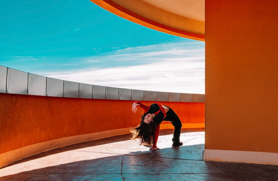 Teenager dancing energetically outdoors by terracotta architecture