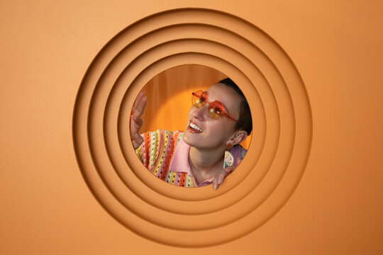 Smiling woman with retro sunglasses in orange circular fashion portrait