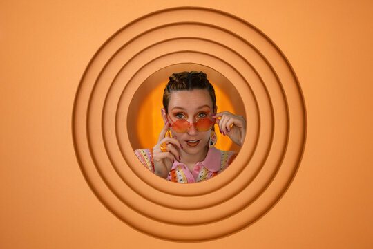 Surprised woman with sunglasses posing in creative orange setting