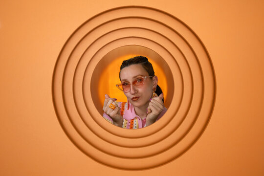 Stylish person posing with sunglasses against orange circular background