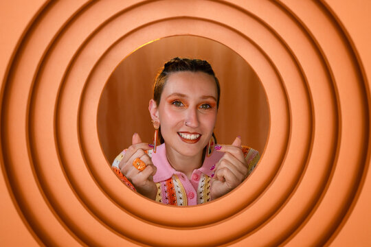 Smiling woman making heart hand gesture with orange background