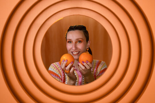 Playful fashion portrait with orange fruit and circular background