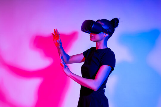 Woman in a studio wearing VR glasses with neon lights creating a futuristic atmosphere