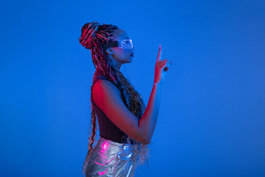 Woman with braids wearing AR glasses posing in blue studio