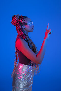 Woman with AR glasses gesturing in studio with blue background