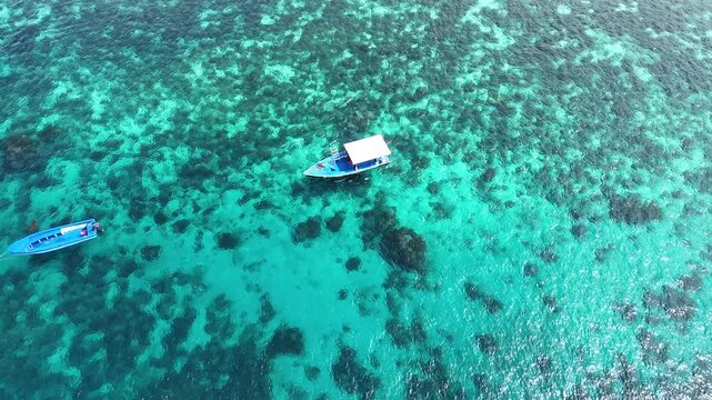Drone POV of one traditional outrigger boat on calm ocean with coral reefs below, Bohol island