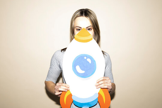 Woman holding handmade paper rocket representing ambition and growth