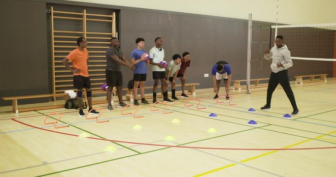 Diverse male team watching African-American coach stepping, teaching shuffle by net, copy space